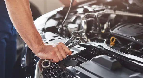 Technician working in a car engine bay &mdash; automotive components