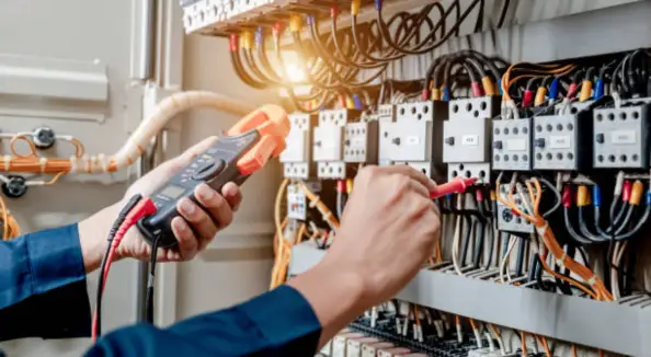 Electrician testing an electrical control panel with a multimeter